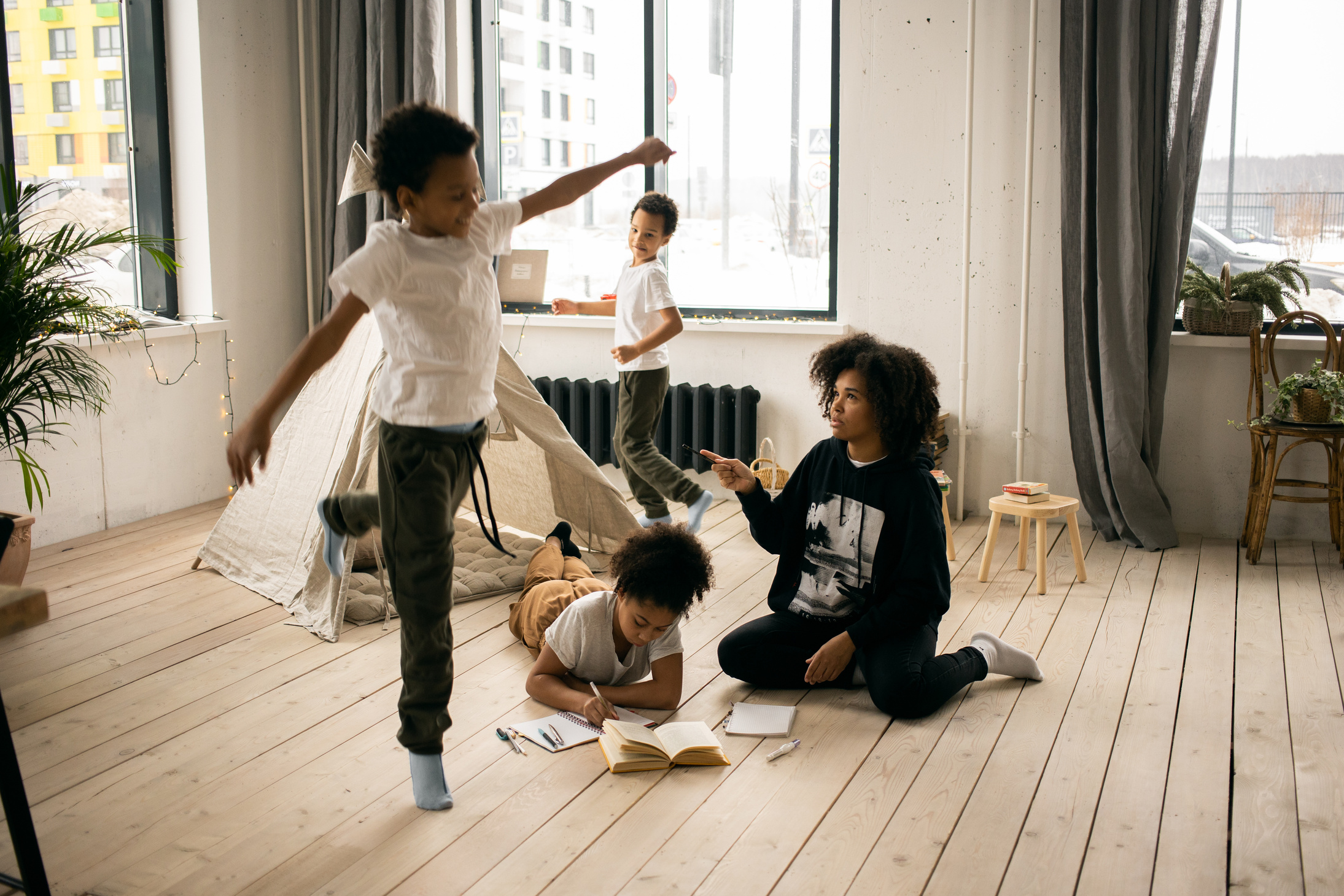 Black mother in room with playing kids